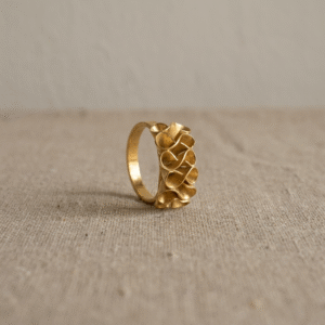 Adjustable gold-plated bronze Golden Bloom Ring with sculptural flower petals on a natural fabric background.