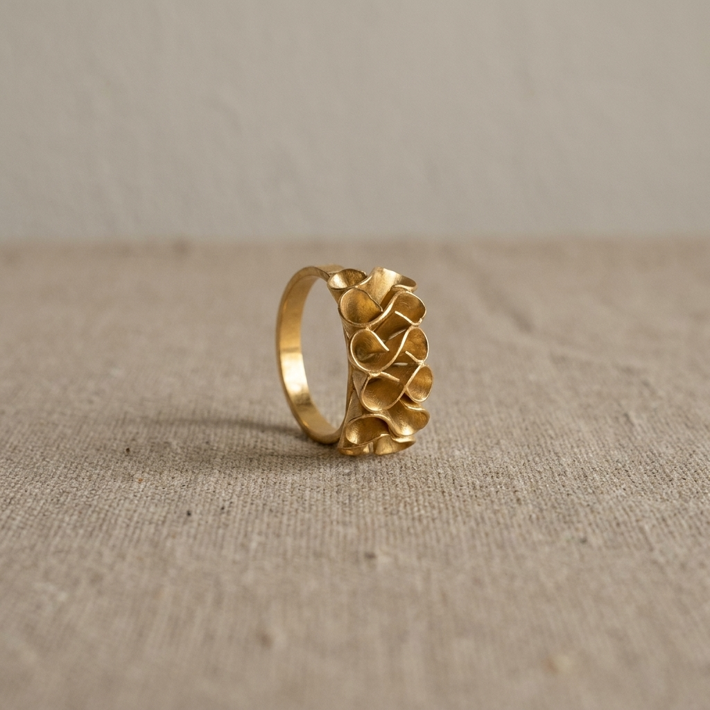 Adjustable gold-plated bronze Golden Bloom Ring with sculptural flower petals on a natural fabric background.