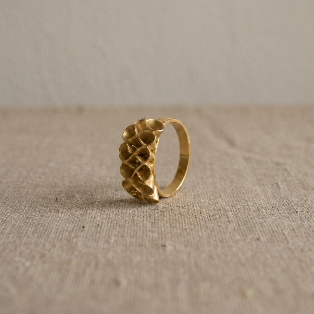 Adjustable gold-plated bronze Golden Bloom Ring with sculptural flower petals on a natural fabric background.
