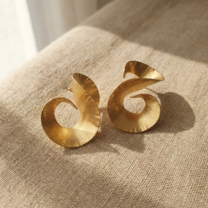 Gold-plated bronze Ancestral Spiral Earrings with sculptural spiral design on a natural background.