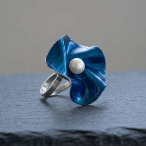 Adjustable silver Azure Bloom Ring with a sculptural blue flower and pearl center on a neutral background.