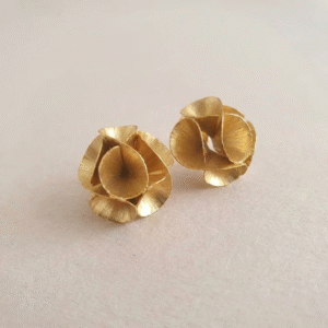 Large gold-plated bronze Motion Bloom Earrings with sculptural flower design on a light natural background.