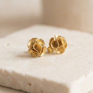 Small gold-plated bronze Motion Bloom Earrings with sculptural flower design on a light natural background
